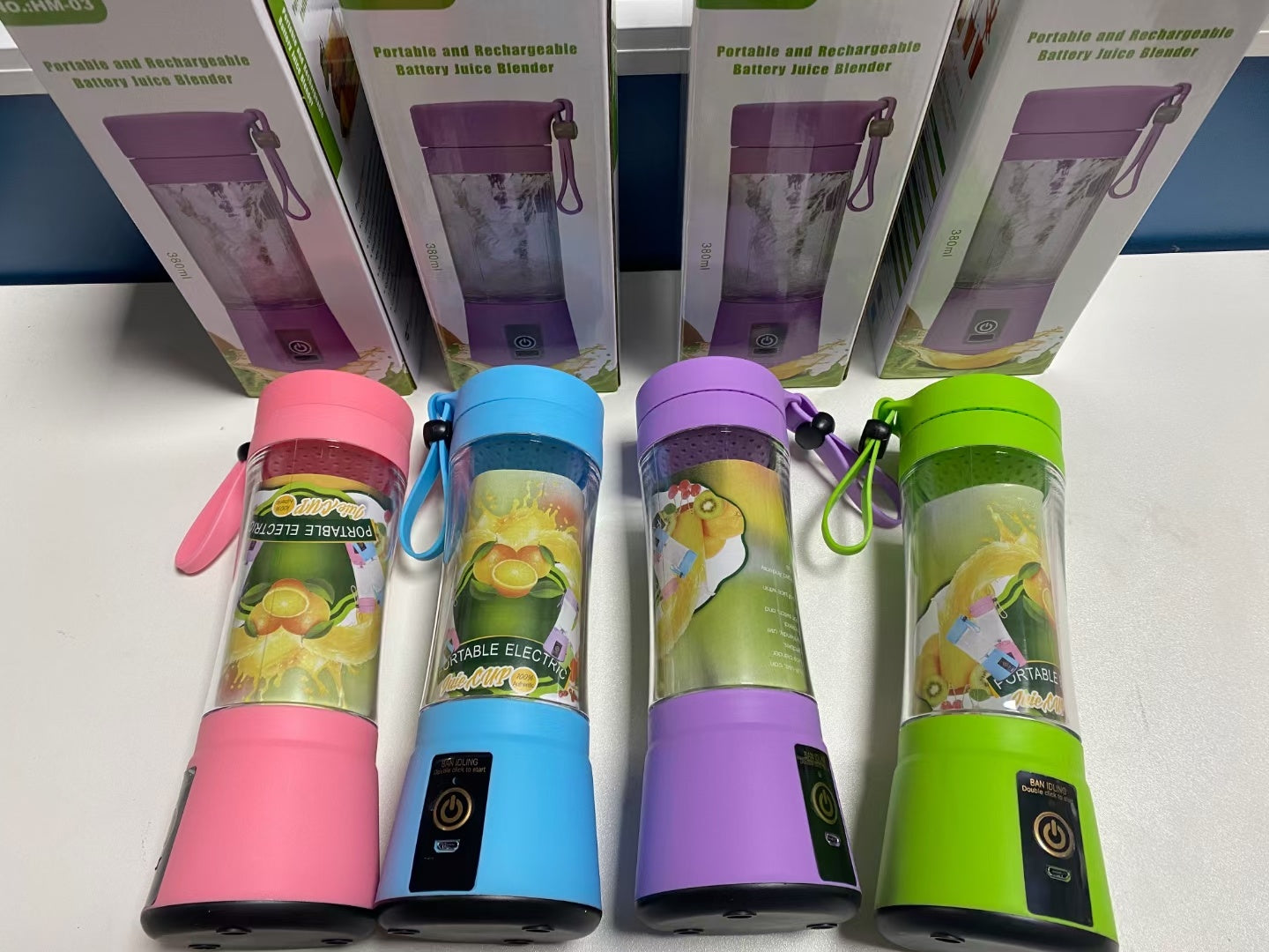 Four portable juice blenders with colorful lids on a white surface.